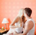 Young Couple Kneeling on Bed Kissing